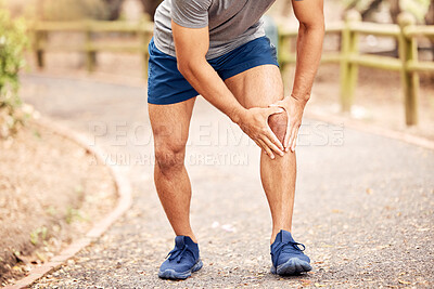 Buy stock photo Shot of an unrecognisable man experiencing knee pain while working out in nature