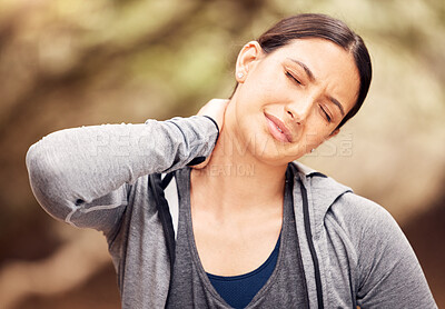 Buy stock photo Shot of a young woman experiencing neck pain while working out in nature