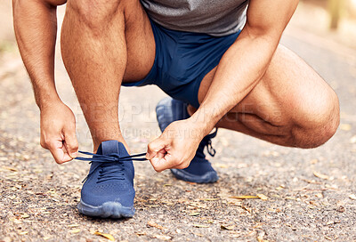 Buy stock photo Shot of an unrecognisable man tying his shoelaces before going for a run in nature