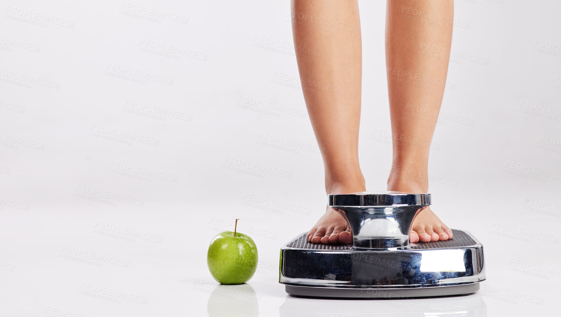 Buy stock photo Cropped shot of a young woman standing on a weight scale