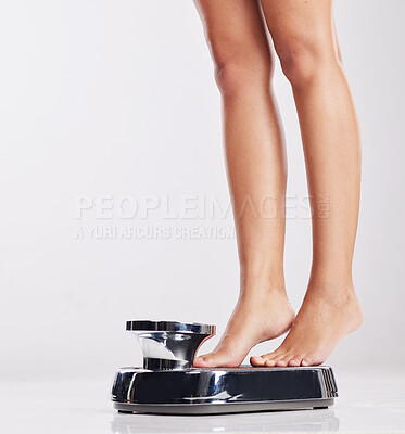 Buy stock photo Cropped shot of a young woman standing on a weight scale