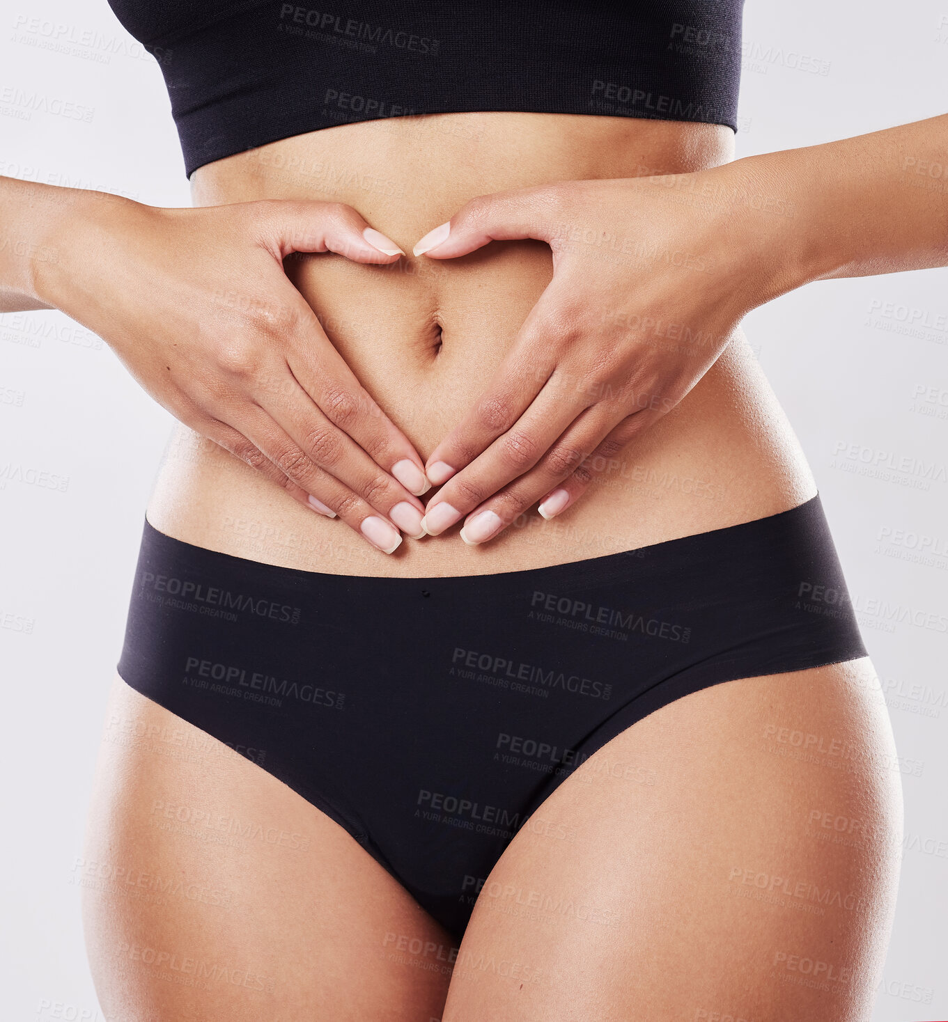 Buy stock photo Cropped shot of a woman forming a heart shape over her stomach