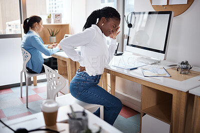 Buy stock photo Shot of a young businesswoman experiencing back pain while working at her desk in a modern office