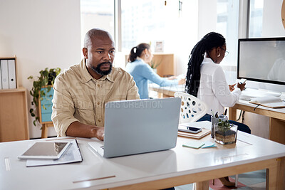 Buy stock photo Shot of a mature businessman using a laptop in a modern office