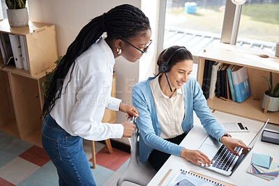 Buy stock photo Shot of two businesswomen using a headset and computer while working in a modern office