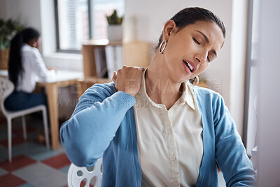 Buy stock photo Shot of a young businesswoman experiencing back pain while working at her desk in a modern office