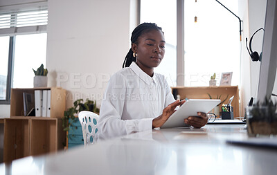 Buy stock photo Shot of a young businesswoman using a digital tablet at her desk in a modern office