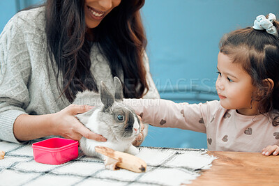 Buy stock photo Mother, smile and child pet rabbit for love, care and feeding healthy animal eating on table in family home. Mom, happy girl and playing with bunny friend for learning and easter holiday celebration