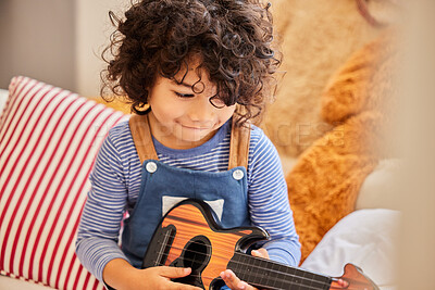 Buy stock photo Break, music and toy guitar with boy in bedroom of home for instrument fun or practice. Audio, learning and sound with happy child playing pretend musician on sofa in apartment to relax for weekend