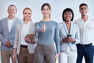 Buy stock photo Portrait of a young businesswoman reaching out to shake hands while surrounded by her team in a modern office