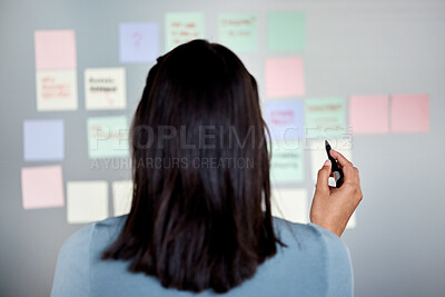Buy stock photo Rearview shot of an unrecognizable woman using sticky notes on a board