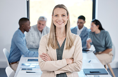 Buy stock photo Portrait of a confident businesswoman standing with her arms crossed in an office while her colleagues have a meeting in the background