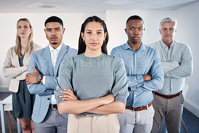 Buy stock photo Portrait of a confident young businesswoman standing with her arms crossed in an office with her colleagues behind her