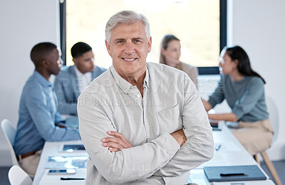 Buy stock photo Portrait of a confident mature businessman standing with his arms crossed in an office while his colleagues have a meeting in the background