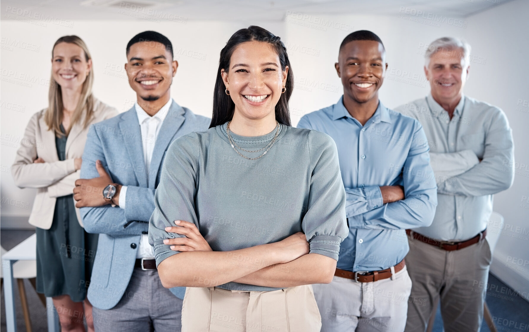 Buy stock photo Portrait of a confident young businesswoman standing with her arms crossed in an office with her colleagues behind her