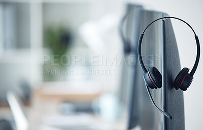 Buy stock photo Closeup shot of a headset resting on a computer monitor in a call centre