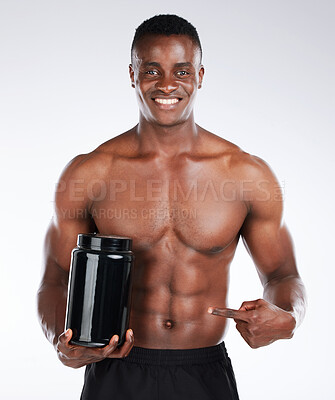 Buy stock photo Shot of a handsome young man standing alone in the studio and holding a container of whey protein