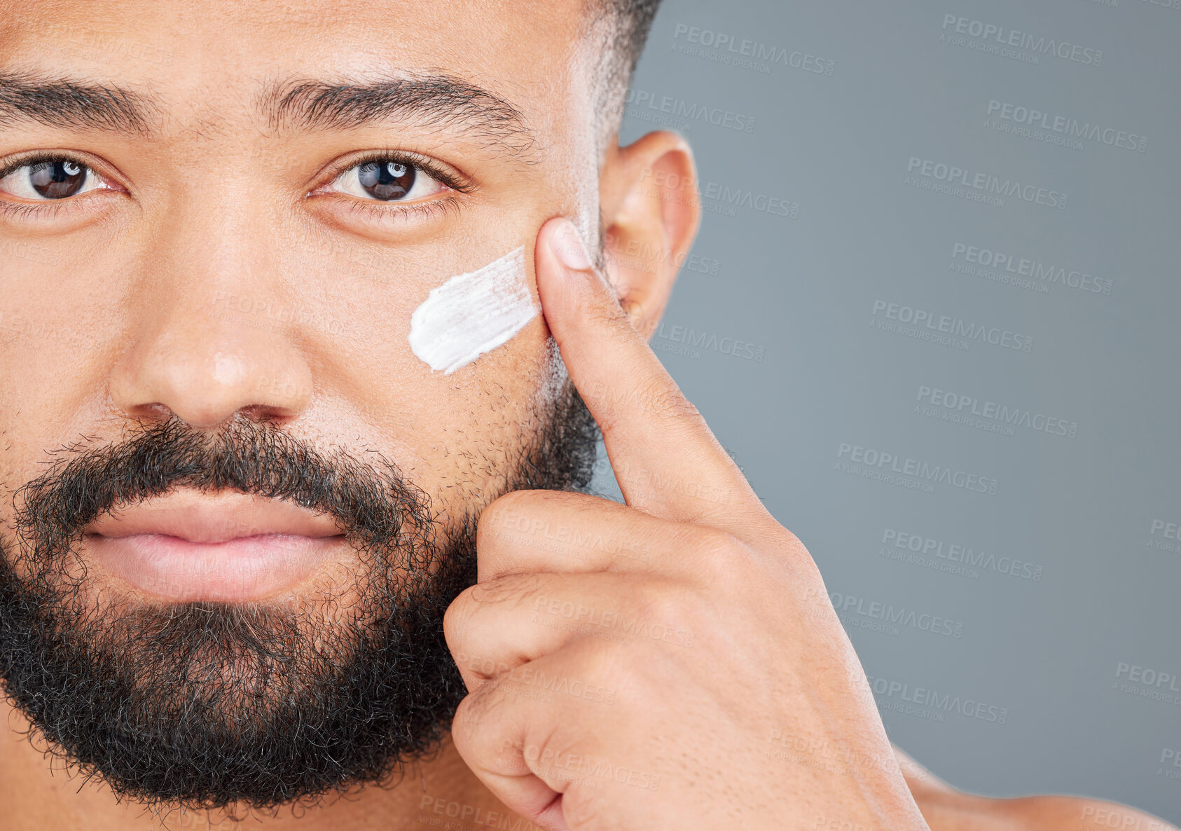 Buy stock photo Finger, cream and portrait of man in studio for skincare, facial treatment and skin tone or hydration. Male person, lotion and sunscreen for uv protection on gray background, closeup and grooming.