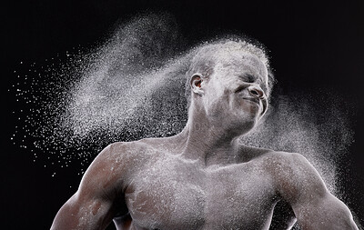 Buy stock photo Artistic shot of a muscular young man posing with white powder in studio against a dark background