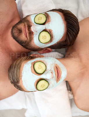 Buy stock photo Shot of a young couple wearing cucumbers on their eyes in a spa