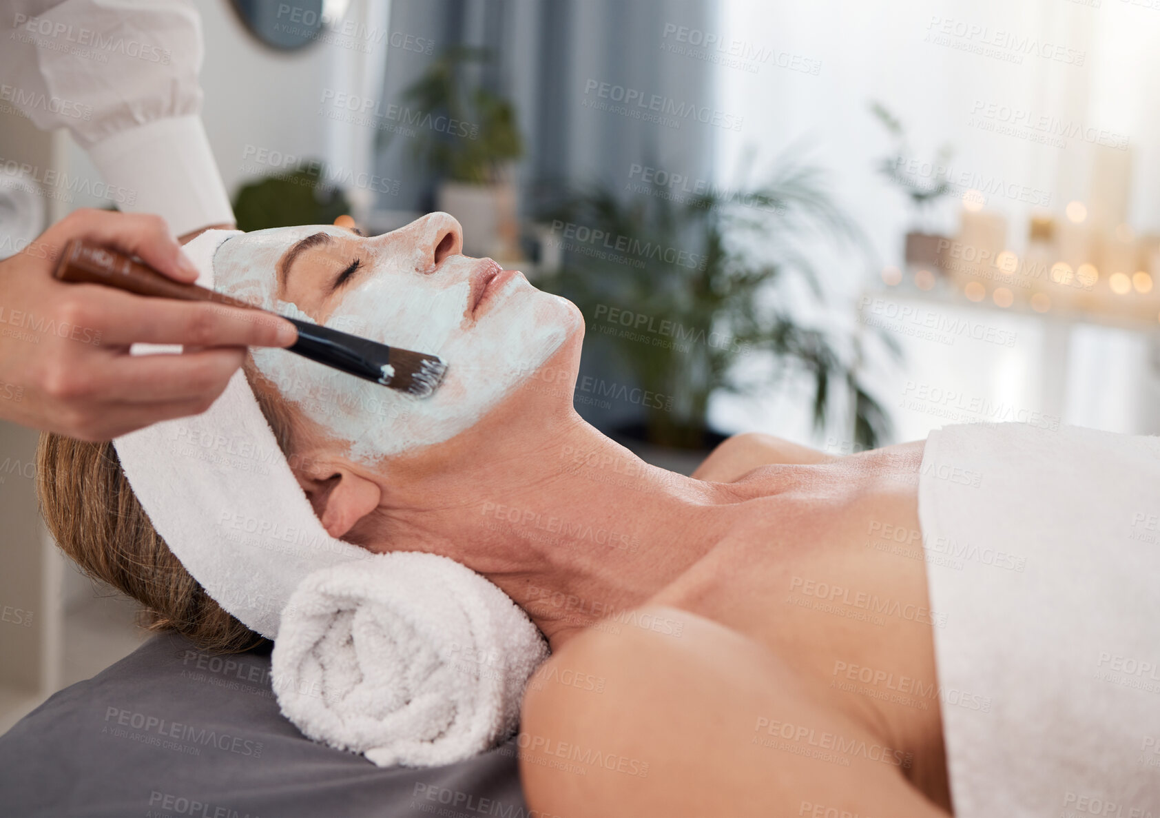 Buy stock photo Face mask, hand and woman at spa with skincare for organic treatment, cosmetics or dermatology on bed. Relax, mature client and masseuse with brush for beauty, wellness or luxury facial at resort