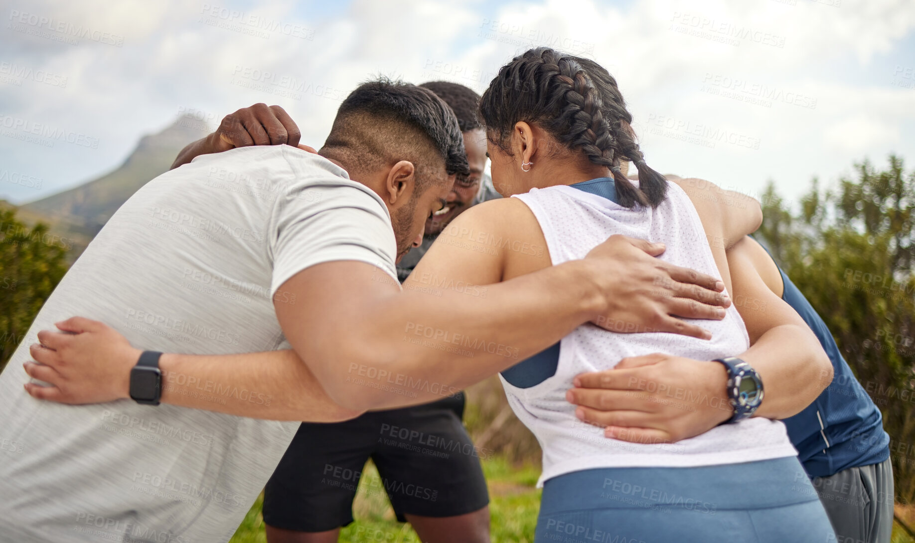 Buy stock photo Shot of a group of sporty young people standing together in a huddle while exercising outdoors