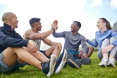 Buy stock photo Shot of a group of sporty young people giving each other a high five while taking a break from exercising outdoors