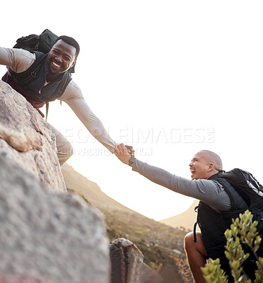 Buy stock photo Cropped shot of a handsome young man helping his friend along a mountain during their hike