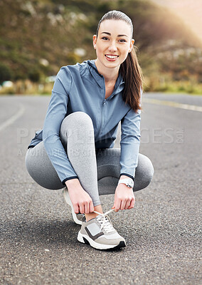 Buy stock photo Shot of a woman tying her shoelaces while out for a run on a road