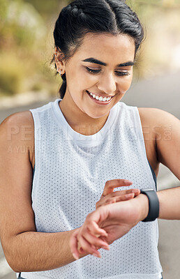 Buy stock photo Shot of a young woman checking her watch while out for a run