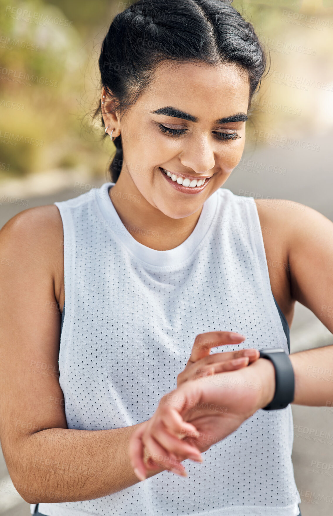 Buy stock photo Shot of a young woman checking her watch while out for a run