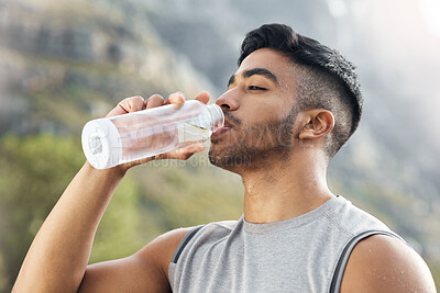 Buy stock photo Shot of a man drinking water while out for a workout