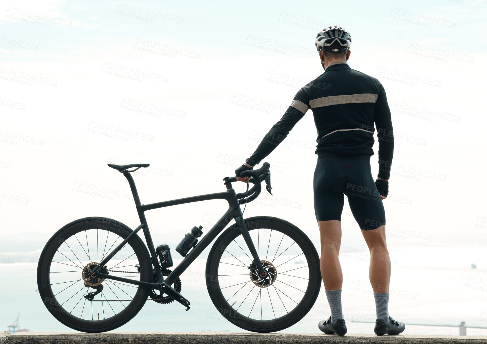 Buy stock photo Rearview shot of an unrecognizable man taking a break to admire the view while cycling outdoors