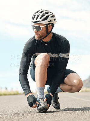 Buy stock photo Full length shot of a handsome mature man tying his laces while cycling outdoors