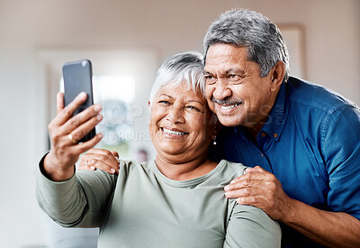 Buy stock photo Shot of a happy senior couple using a cellphone for a selfie together at home