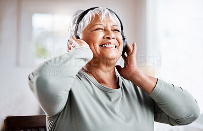 Buy stock photo Shot of a beautiful senior woman listening to music while sitting on the sofa at home