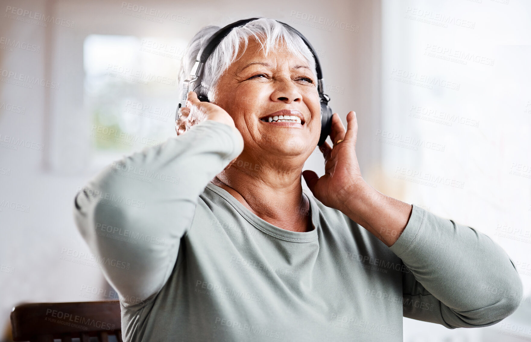 Buy stock photo Shot of a beautiful senior woman listening to music while sitting on the sofa at home