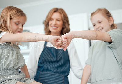 Buy stock photo Closeup shot of two little girls giving each other a fist bump while baking with their grandmother at home