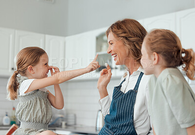 Buy stock photo Shot of a grandmother playing with flour while baking with her two granddaughters at home