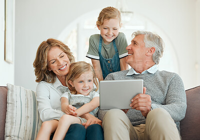 Buy stock photo Shot of a senior couple sitting on the sofa together and bonding with their grandchildren while using a digital tablet