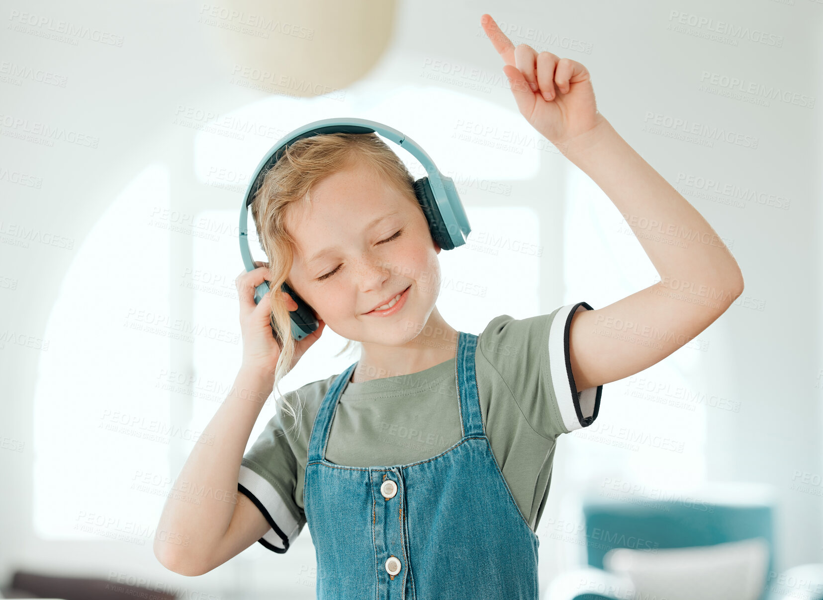 Buy stock photo Shot of an adorable little girl standing alone at home and listening to music through headphones