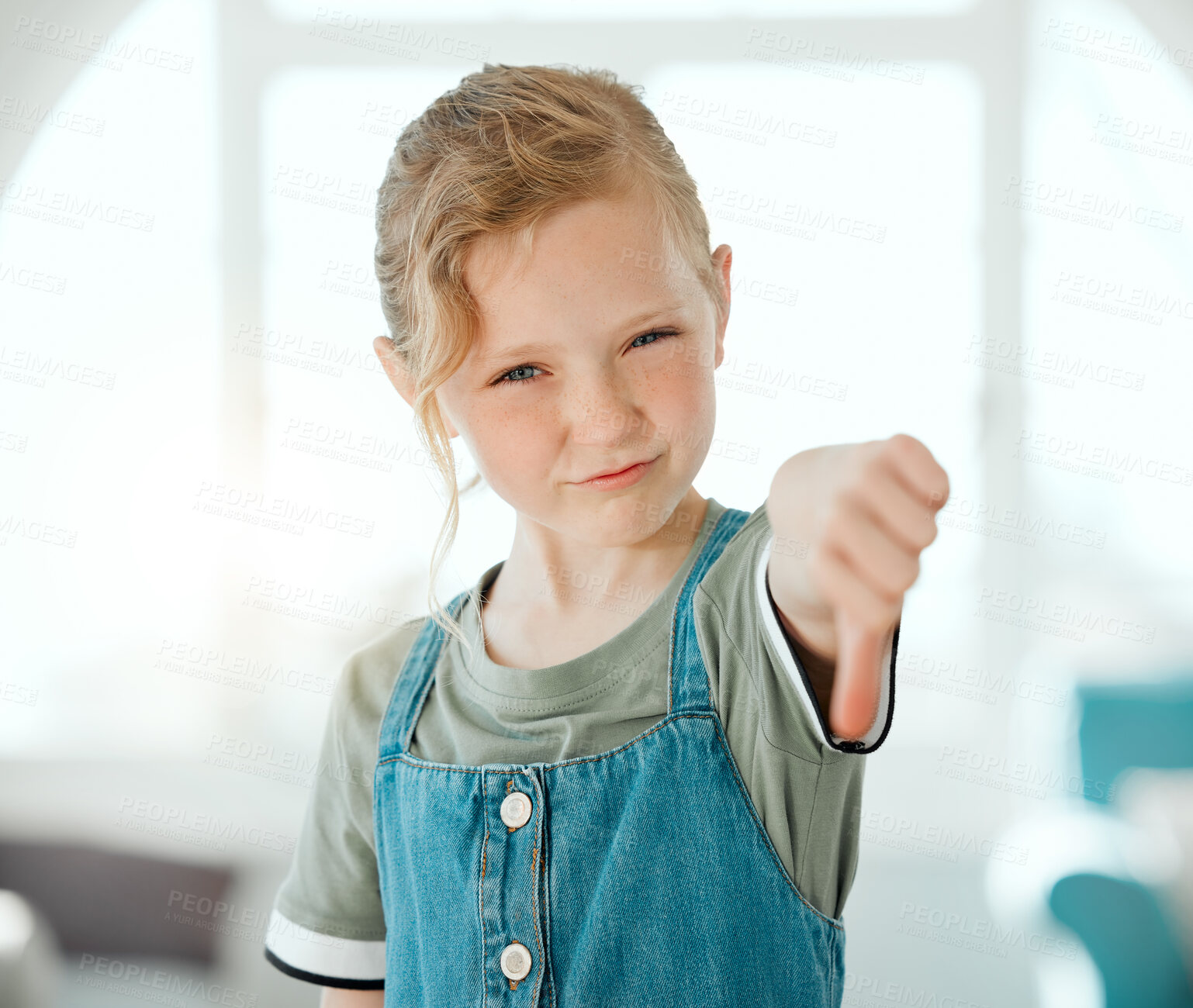 Buy stock photo Shot of an adorable little girl standing alone at home and showing a thumbs down