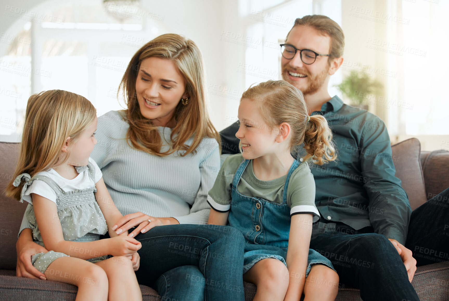 Buy stock photo Shot of young family sitting on the sofa at home together and bonding