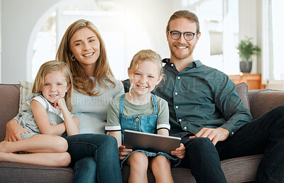 Buy stock photo Shot of a young family sitting on the sofa together and bonding while using technology