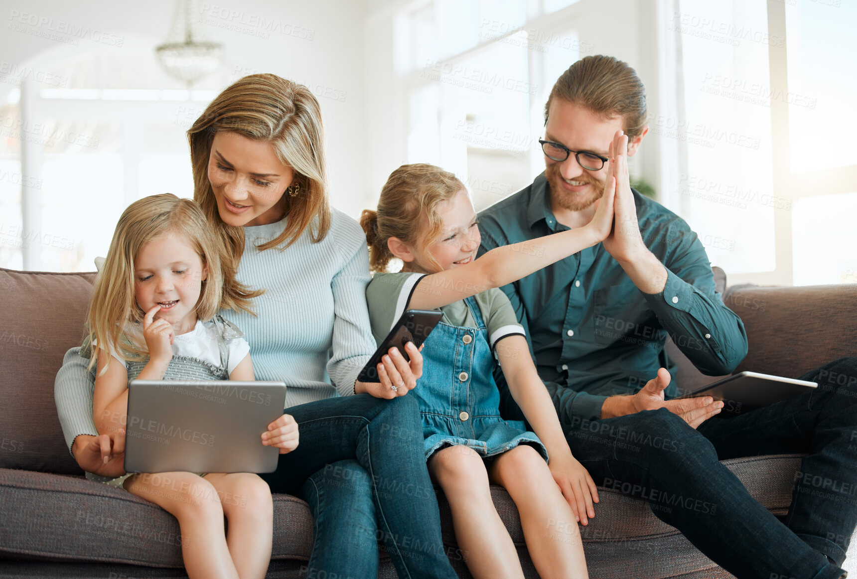 Buy stock photo High five, phone and tablet with family on sofa in living room of home together for streaming success. Conversation, motivation or support with mom, dad and girl child in apartment for education