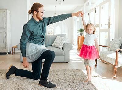 Buy stock photo Full length shot of an adorable little girl wearing a tutu and dancing with her father in the living room