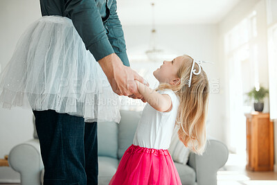 Buy stock photo Shot of an adorable little girl wearing a tutu and dancing with her father in the living room