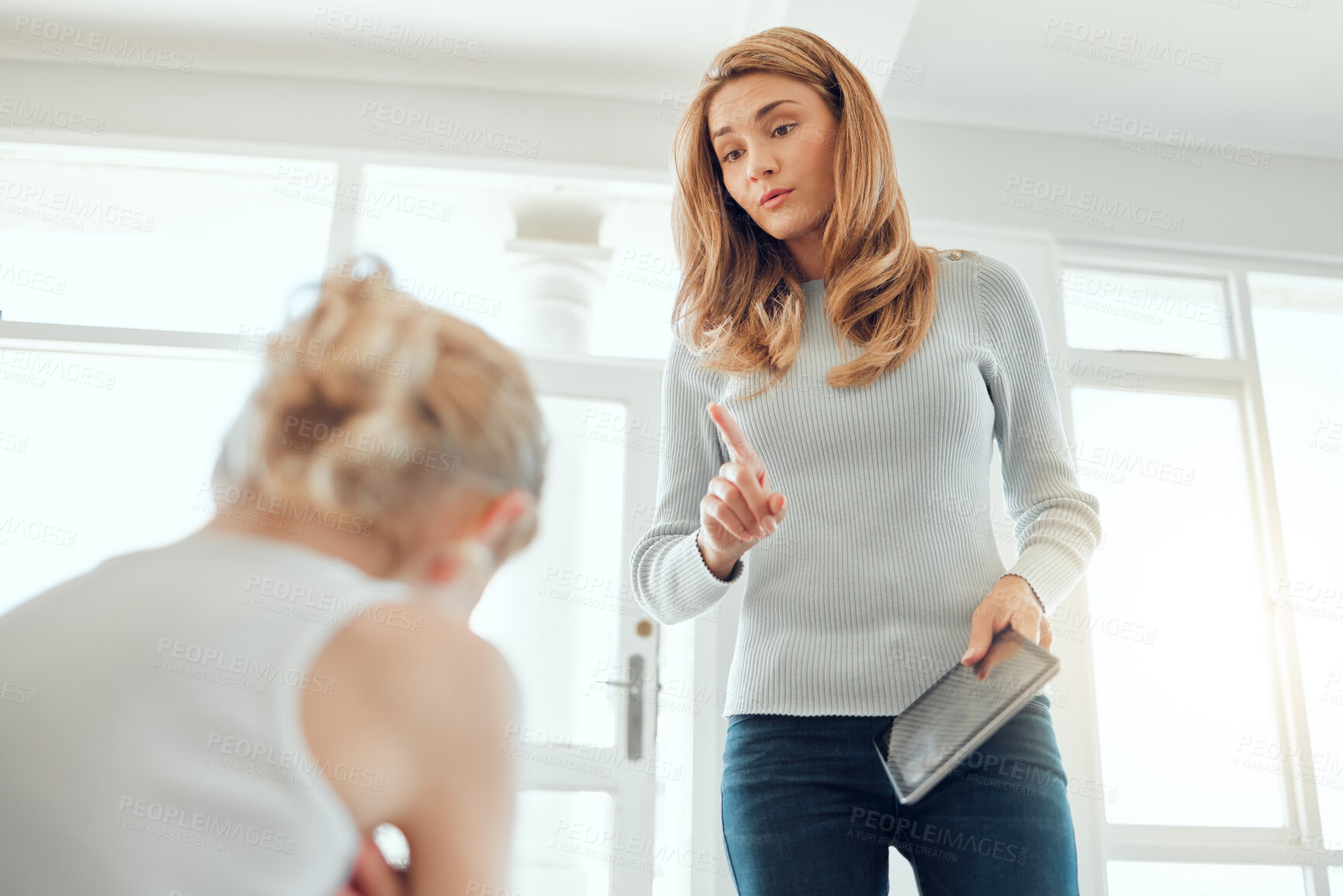 Buy stock photo Shot of a mother fed up with her daughters bickering about a digital tablet at home