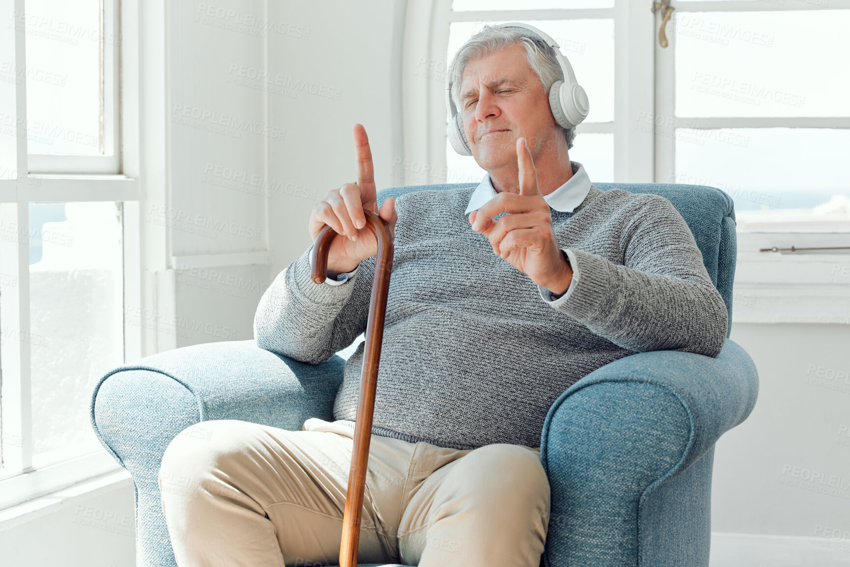 Buy stock photo Shot of an elderly man enjoying some music while sitting in the lounge at home