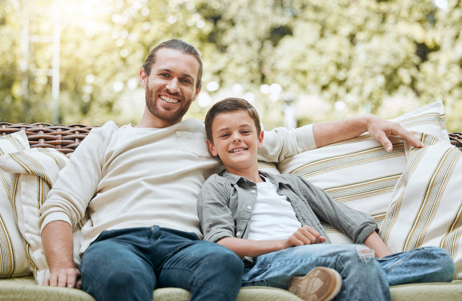 Buy stock photo Dad, boy and happy on patio on couch at home for bonding, support and care in England. People, parent and smile outside with kid or son on portrait for break, relax and rest on sofa with love